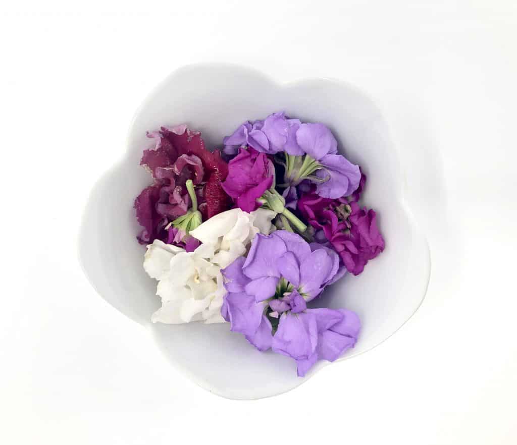a variety pf edible flowers pictured in a bowl