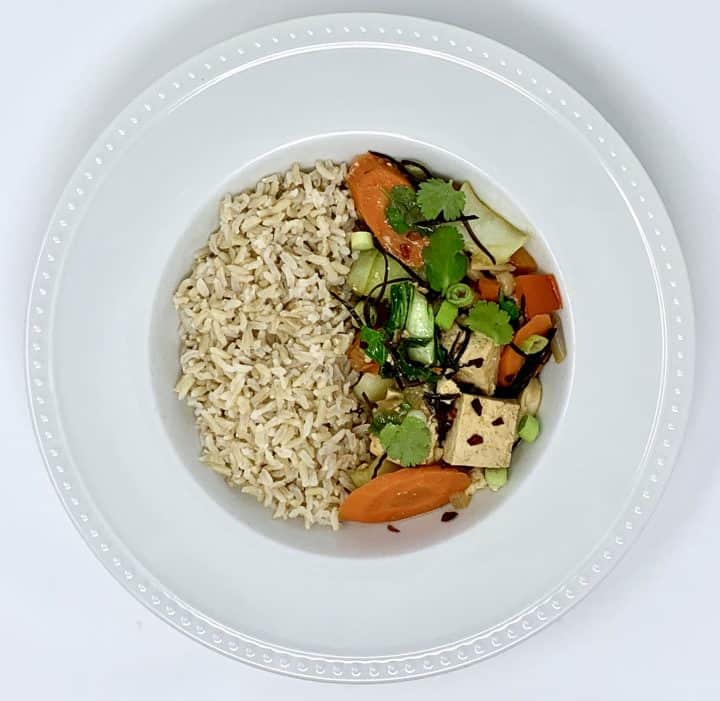 Tofu Veggie Stir-Fry with Arame plated on half the side of a bowl & Basmati Rice on the other half