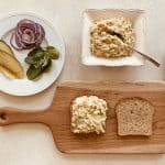 Chickpea Tuna Salad on toast and ready to made into a sandwich with pickles, red onions, and greens