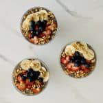 Bowls filled with different types of food on a table, with Lemon chia pudding, and nuts