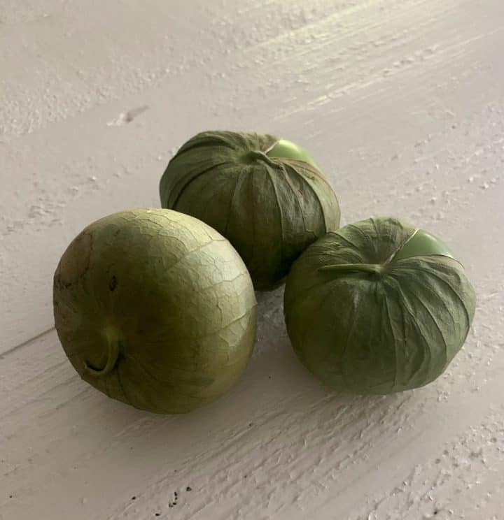 3 tomatillos pictured on table